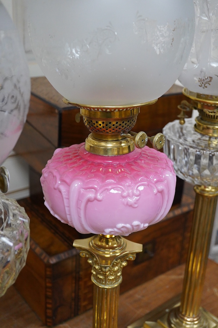 Three Victorian brass column oil lamps, with original brass fittings, glass reservoirs and shades. Tallest 72cm high.
